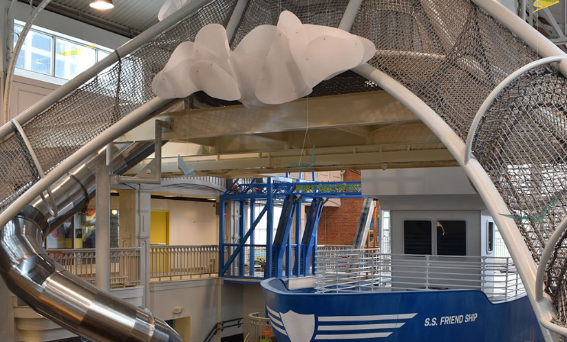 View looking across and down at Port Discovery's multi-floor climber with a swirly slide and multi-level interactive ship exhibit