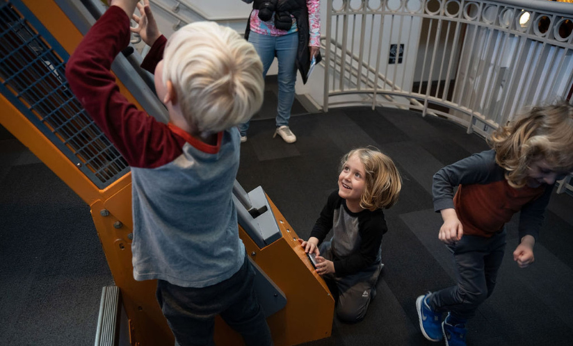 Two children work together as they stack foam blocks on a pretend crane in Port Discovery's Port Open Play Area