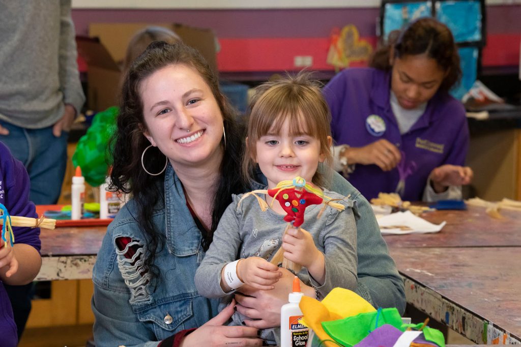 A woman and a child holding up a project and smiling