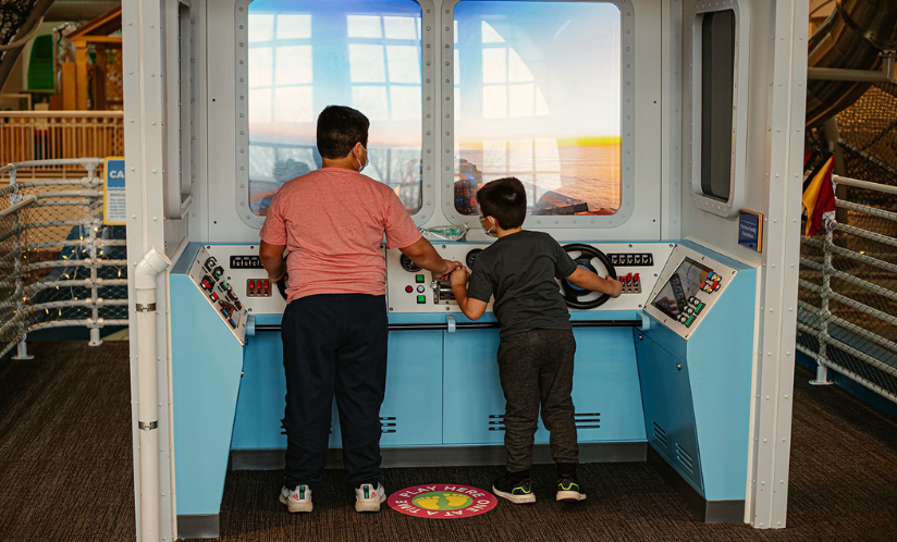 Two children playing together as they pretend to steer Port Discovery's giant S.S. Friendship exhibit across a pretend sea