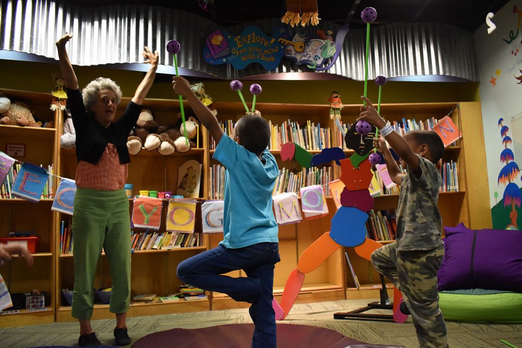 An adult and several children take part in a group yoga program