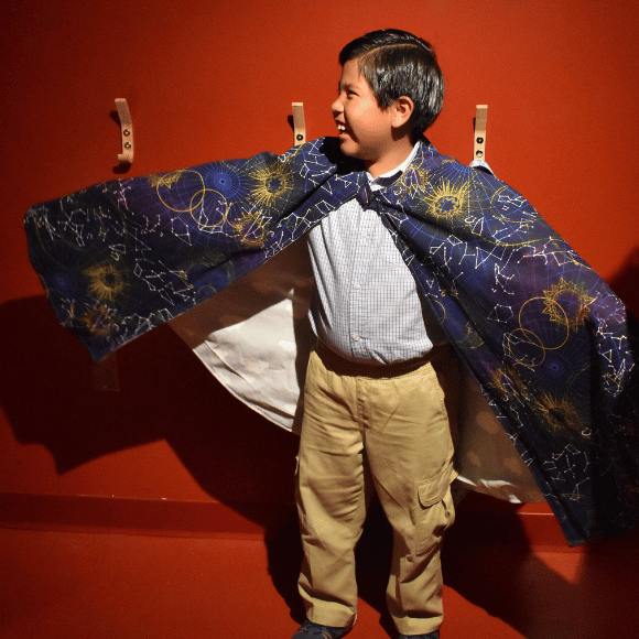 A boy poses in The Playhouse at Port Discovery, wearing a magicians costume