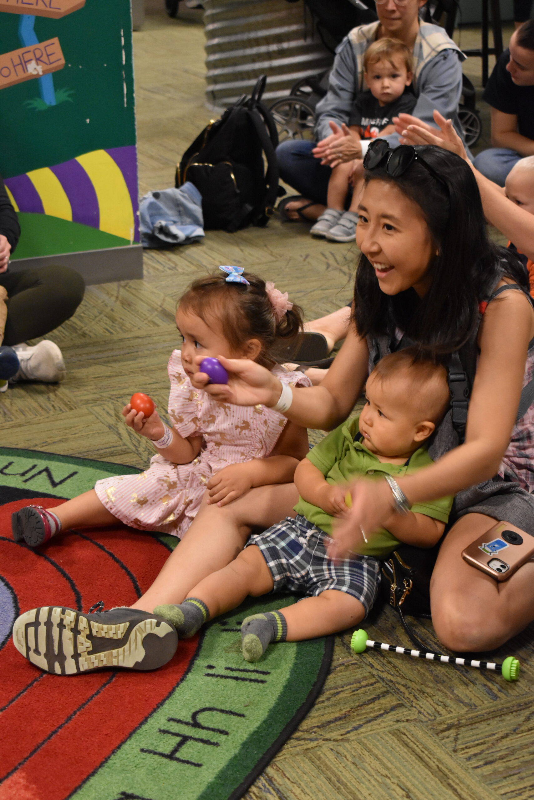 woman, little girl, and baby on floor shaking musical instruments