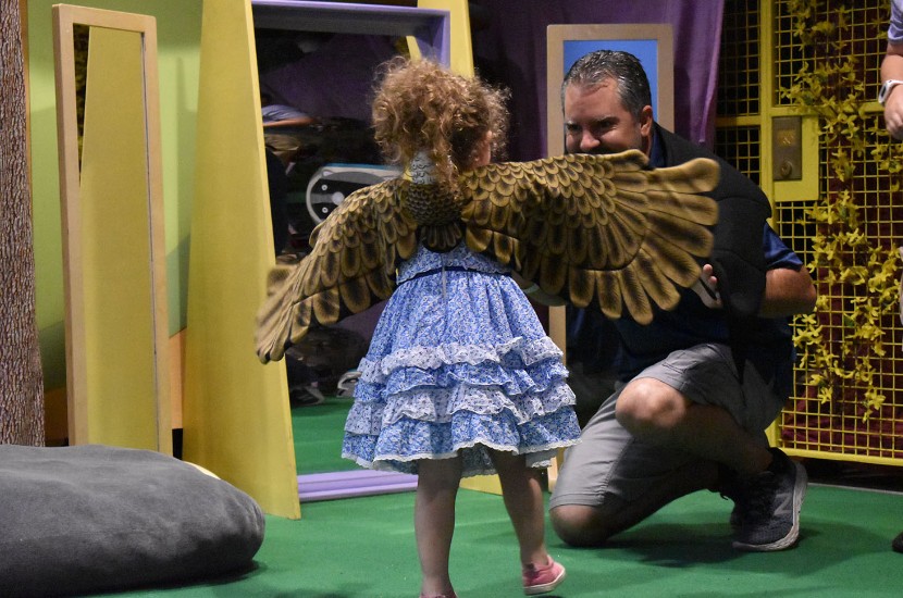 A child wearing a costume that resembles bird wings playing with an adult wearing a costume resembing wings