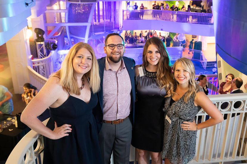 A group of adults smiling as they enjoy attending a private event at Port Discovery