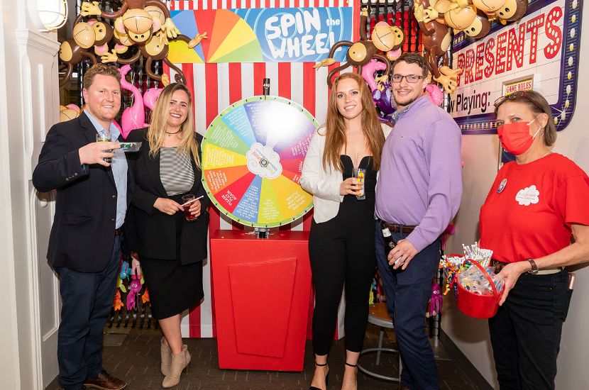 A group of adults attending Port Discovery's Play It Forward fundraising event standing by a carnival game
