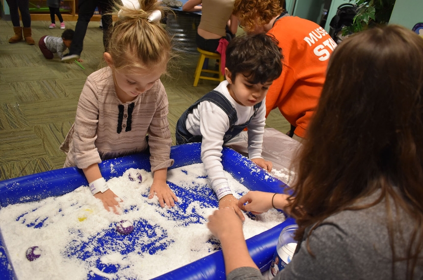 Two children taking part in a sensory activity where they can touch and feel sensory materials