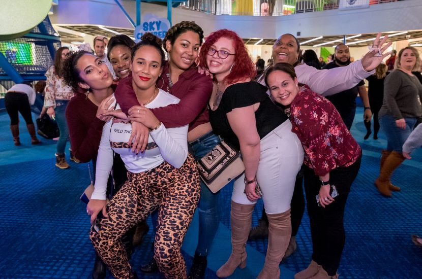A group of adults attending a Port Discovery fundraising event hug and smile for the camera