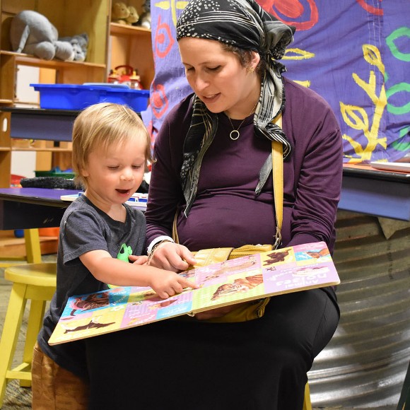 A child and adult sit and read together in Port Discovery's Oasis exhibit