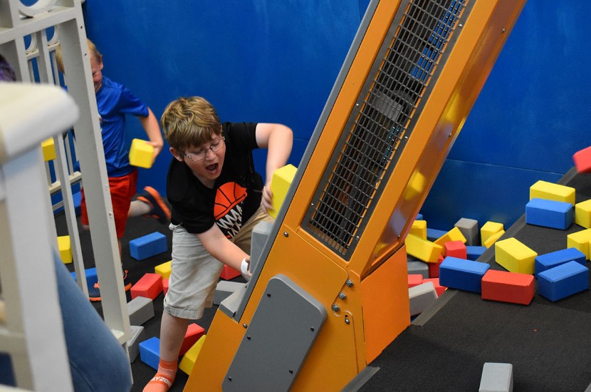Excited child stacking foam blocks on an interactive cargo loader in one of Port Discovery's interactive play areas