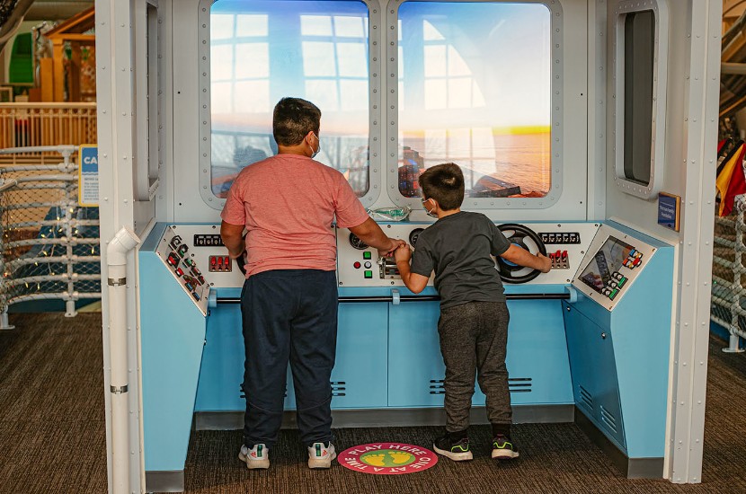 Two children playing together as they pretend to steer Port Discovery's giant S.S. Friendship exhibit across a pretend sea