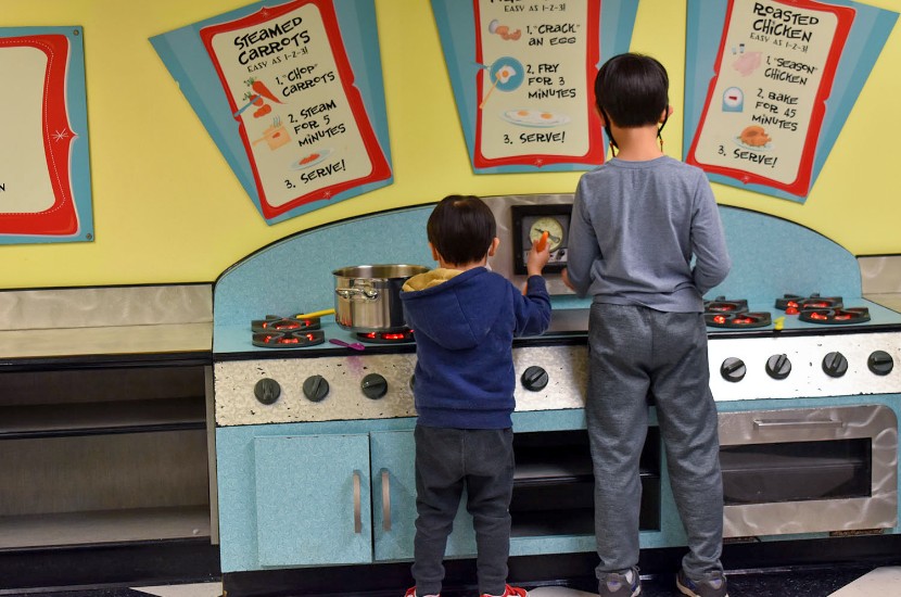 Two children standing and pretending to cook on a play stove in Port Discovery's pretend diner