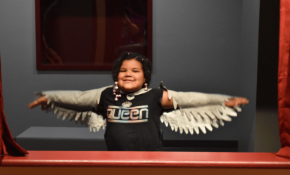 A child wears a white bird costume and poses in Port Discovery Children's Museum's theater exhibit.
