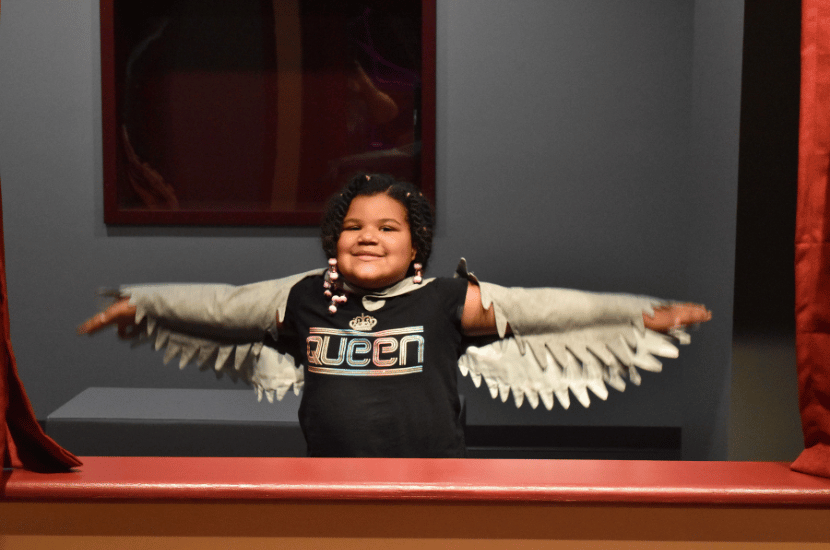 A child wears a white bird costume and poses in Port Discovery Children's Museum's theater exhibit.