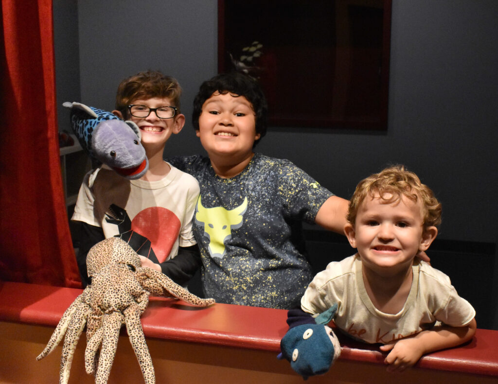 three boys holding sock puppets