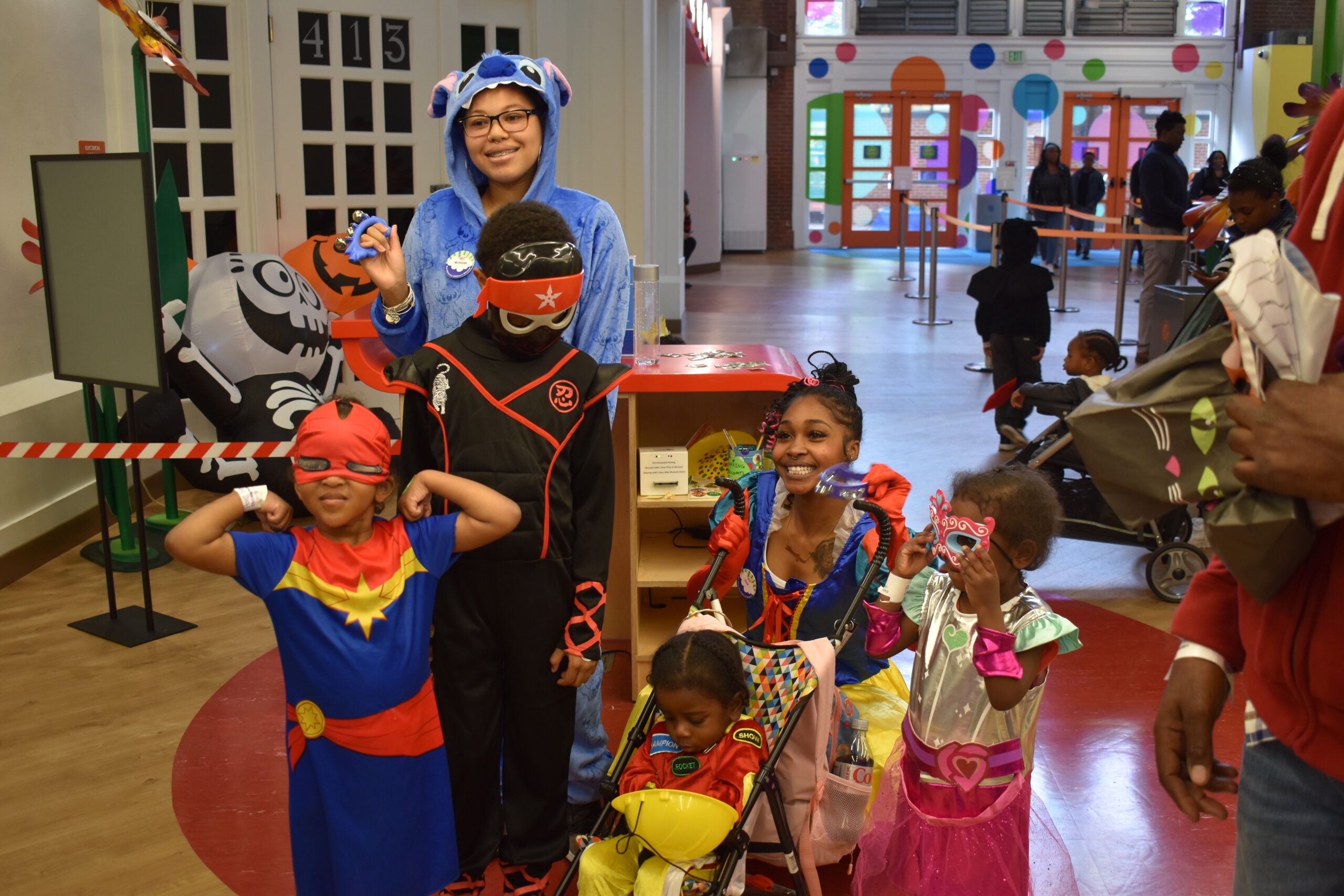 three kids in halloween dressed in costumes standing with two staff members