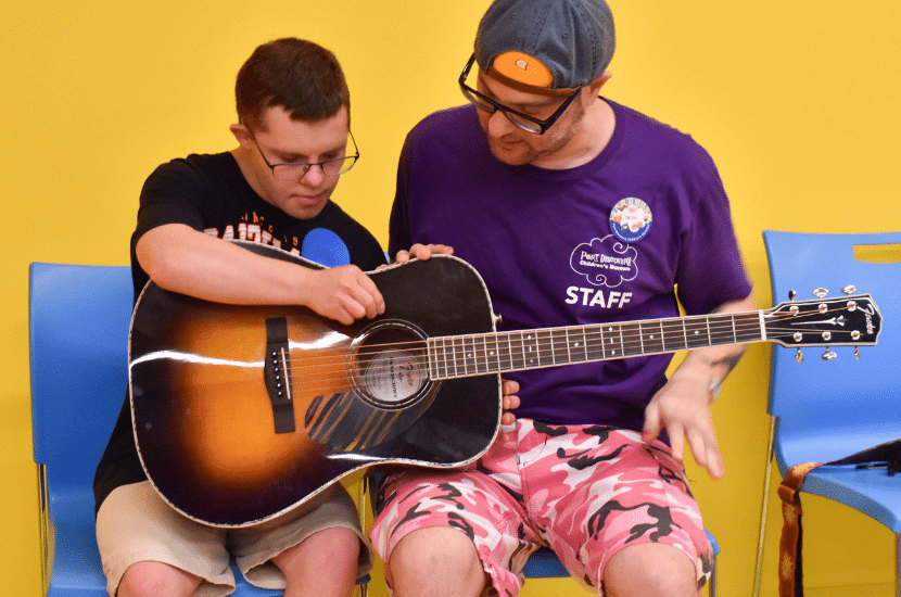 Port Discovery employee and visitor play guitar together