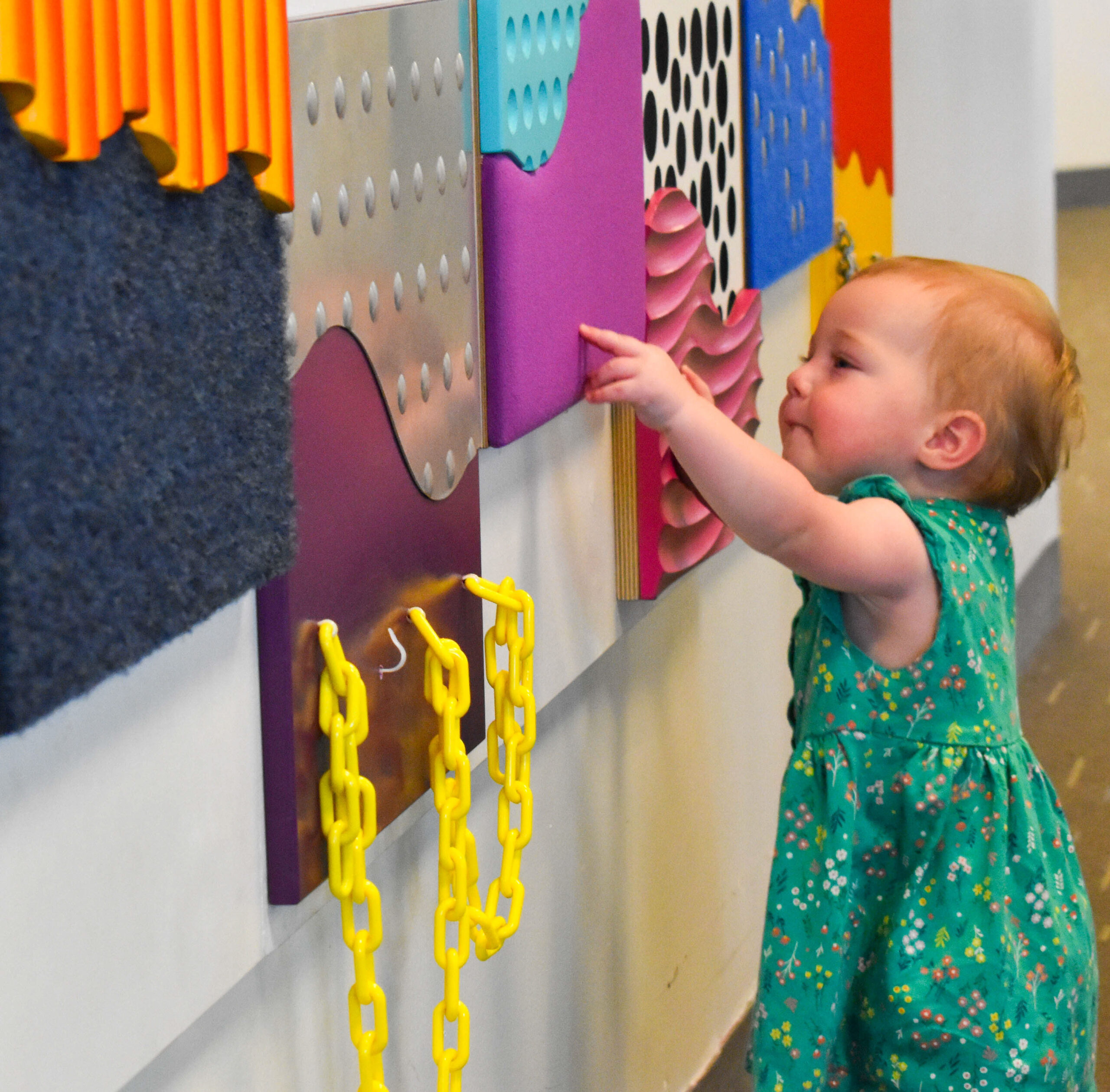 a toddler girl playing with a sensory wall