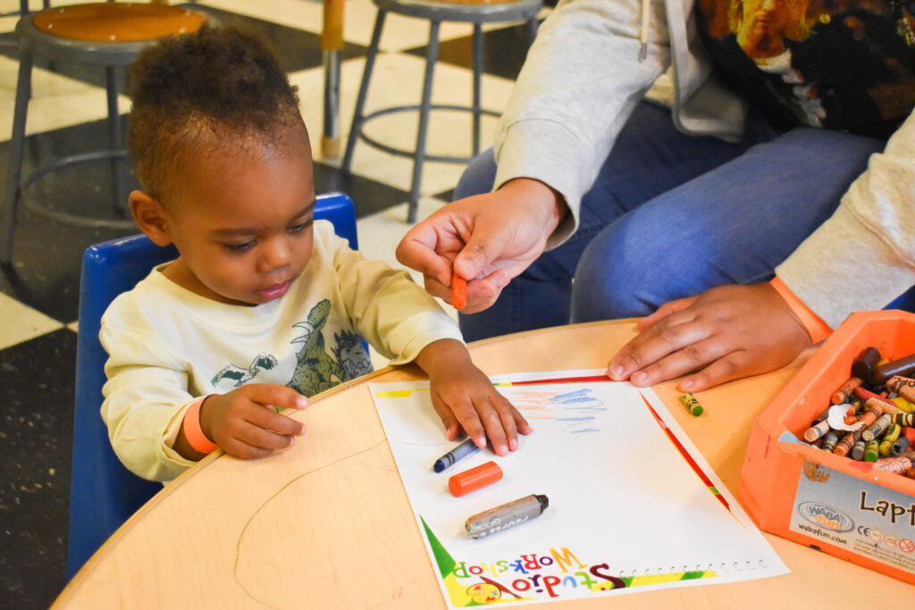 young baby boy holding a crayon and coloring