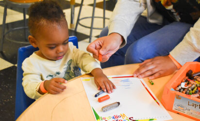 young baby boy holding a crayon and coloring