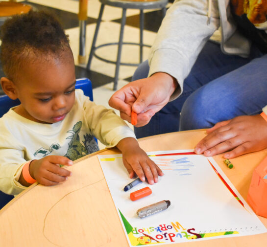 young baby boy holding a crayon and coloring
