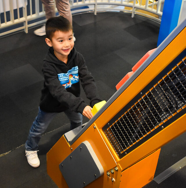 Child putting colorful foam blocks up onto a escalator toy.