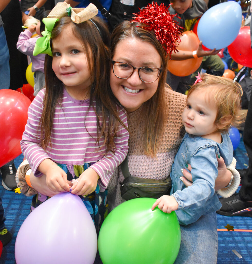 a women with 2 girls holding balloons during new years